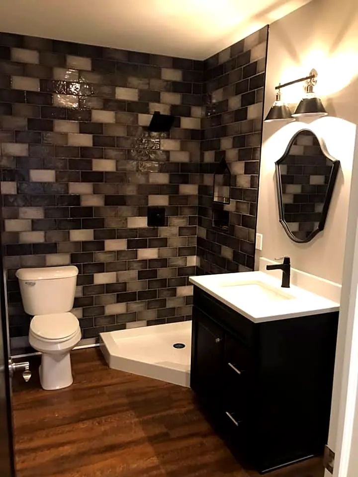 Bathroom with a charcoal tile shower wall, dark vanity and wood-look floor