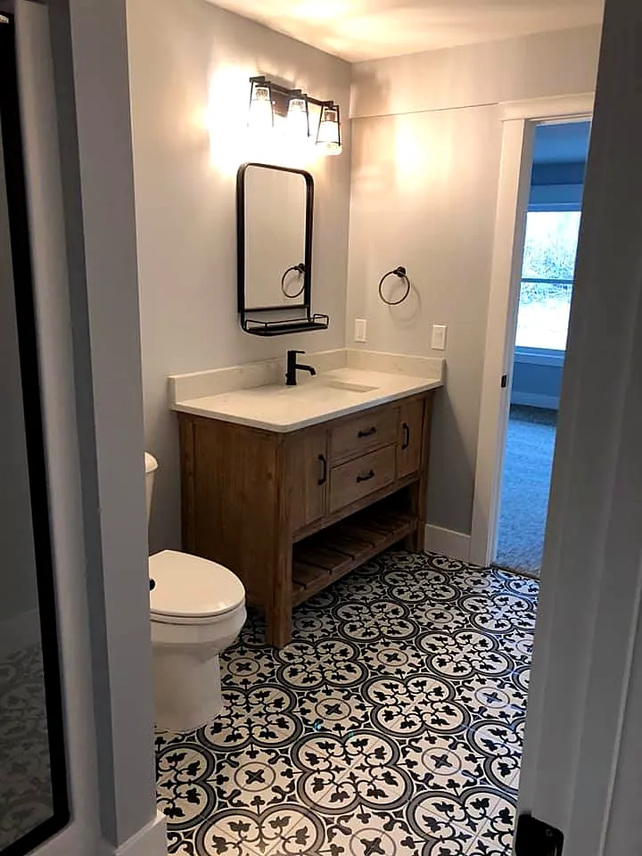 Bathroom with a wood vanity, black fixtures and patterned tile floor
