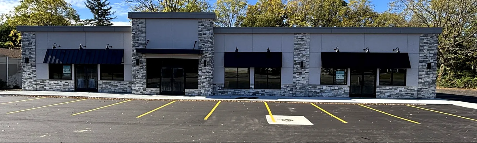 After: RBF Construction's renovated commercial building with stone facade, new awnings and a freshly paved, striped parking lot