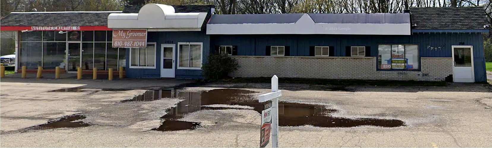 Before: aging single-story commercial building with a cracked, flooded parking lot