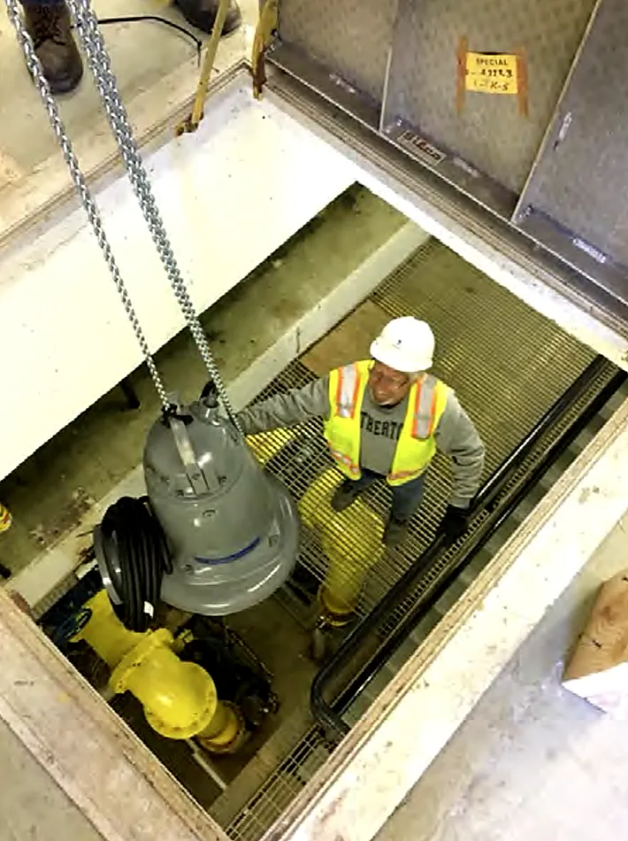 Crew member installing a submersible pump in a lift station