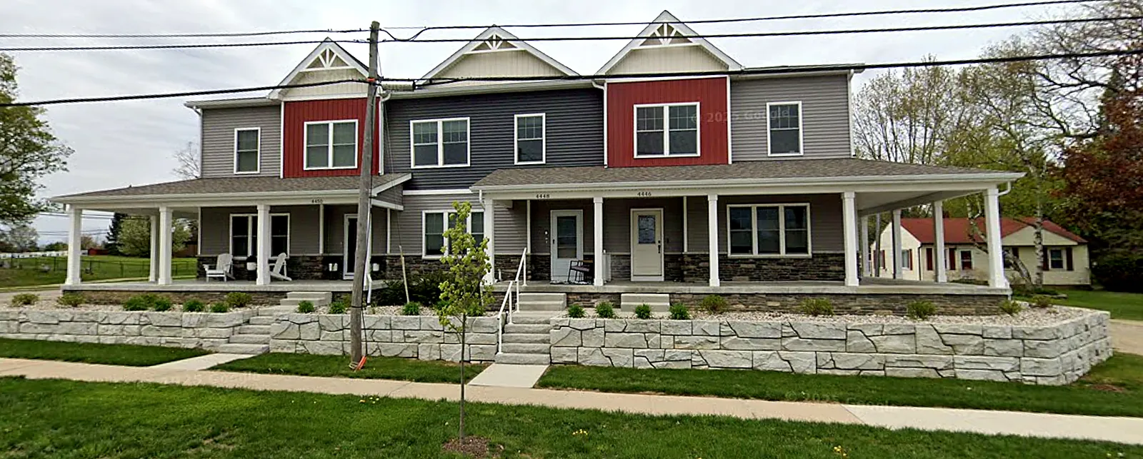 New two-story townhome building with front porches, stone accents and stone retaining walls