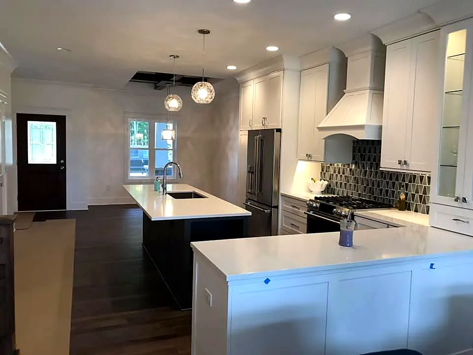 Open kitchen with a large island, patterned tile backsplash and range hood