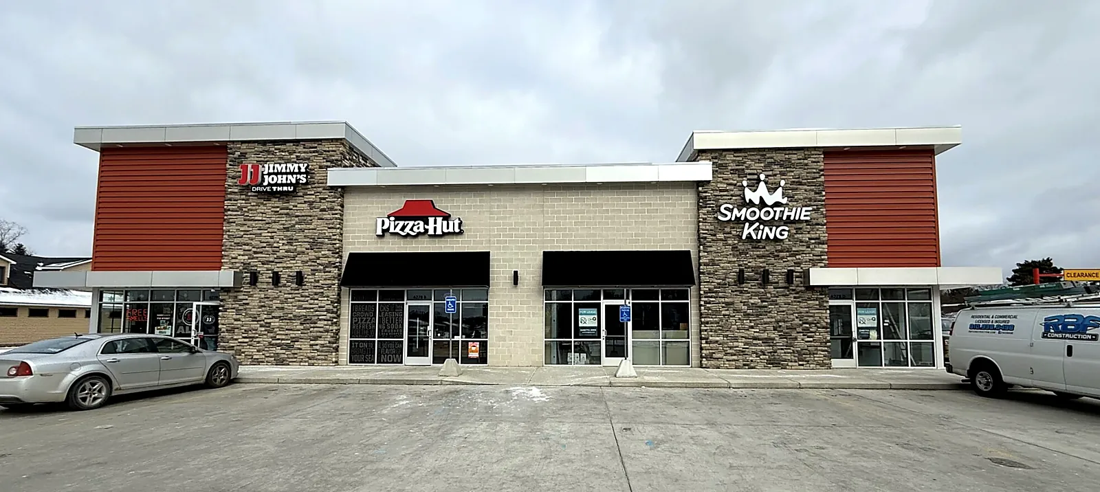 Completed multi-tenant retail building with Jimmy John's drive-thru, Pizza Hut and Smoothie King storefronts, with an RBF Construction van on site