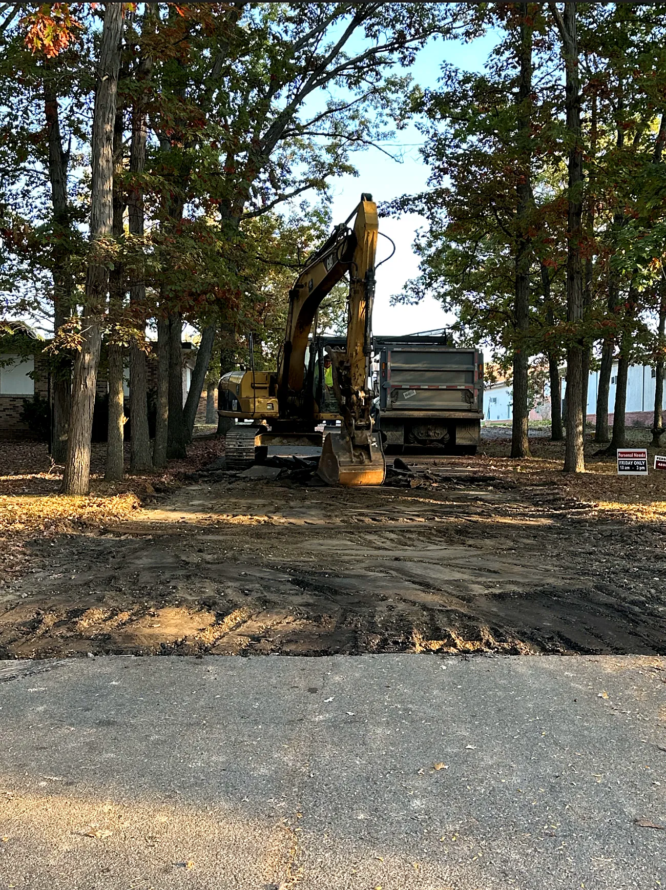 Excavator and dump truck clearing a wooded building site