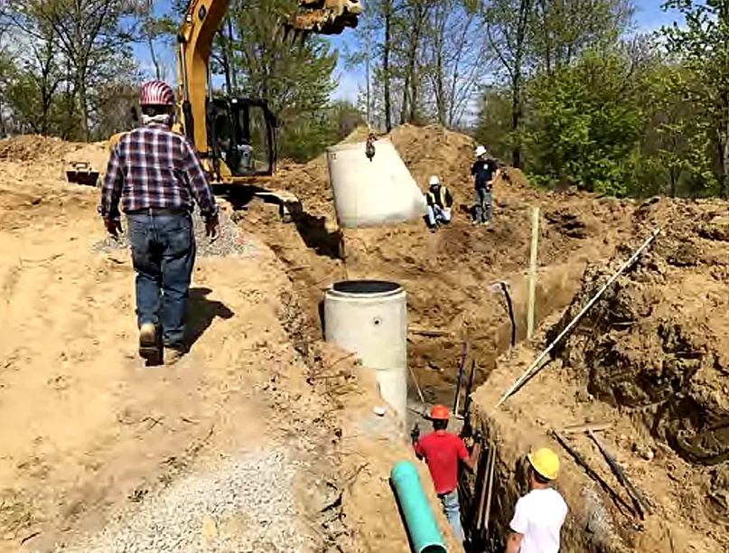 Crew installing manholes and pipe in an underground utility trench