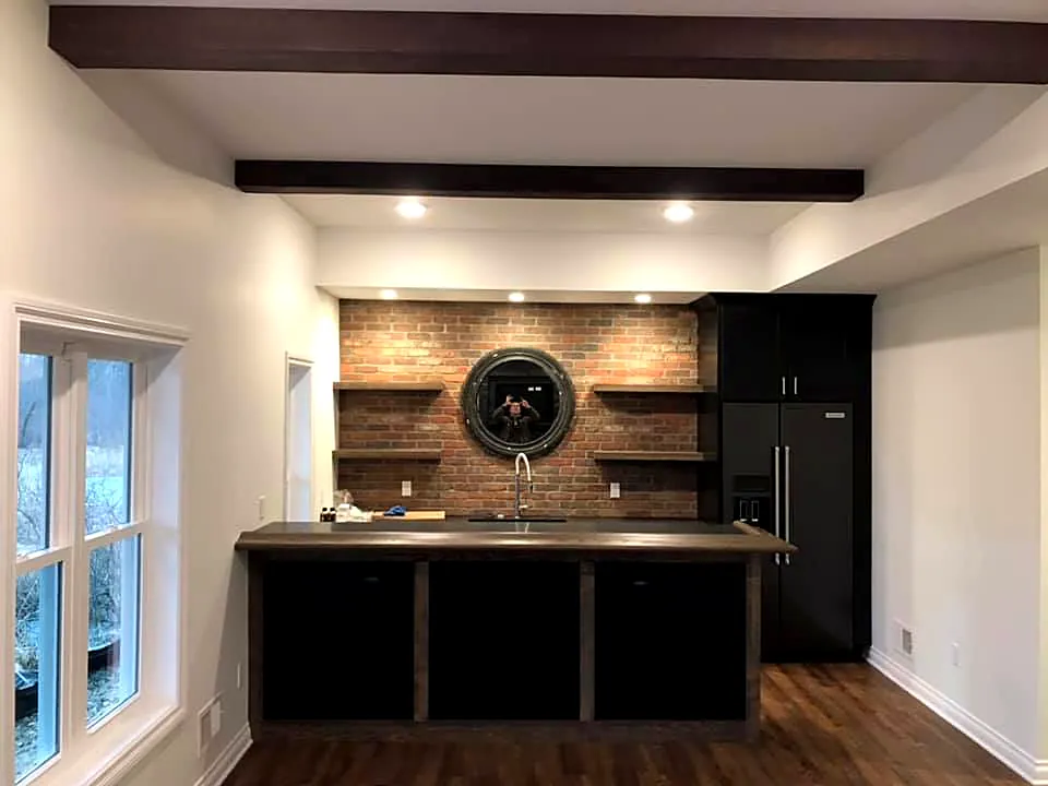 Wet bar with black cabinets and a brick accent wall